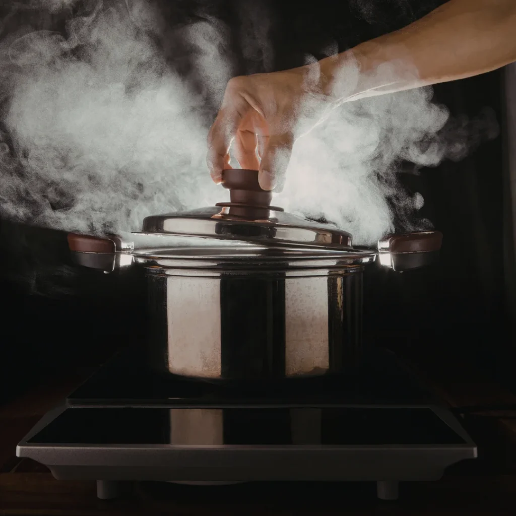 Bananas verdes inteiras com casca dentro de uma panela de pressão de inox.