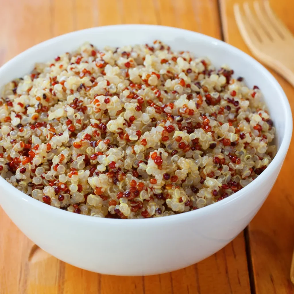 Flocos brancos de quinoa e pequenas sementes de amaranto em uma tigela rústica.